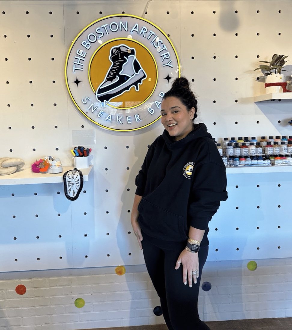 Nandita in the new studio in December 2023, standing in front of the Sneaker Bar logo on the pegboard wall