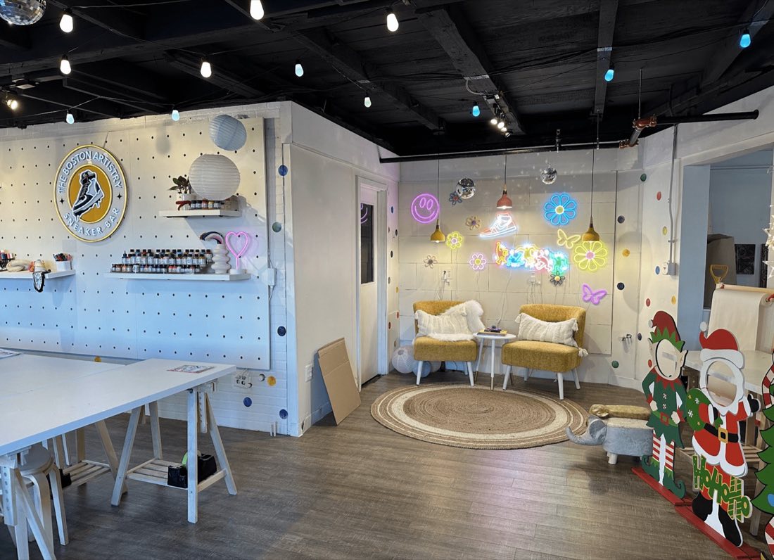 The studio in December 2023: long white tables, a black ceiling and lights strung across the room