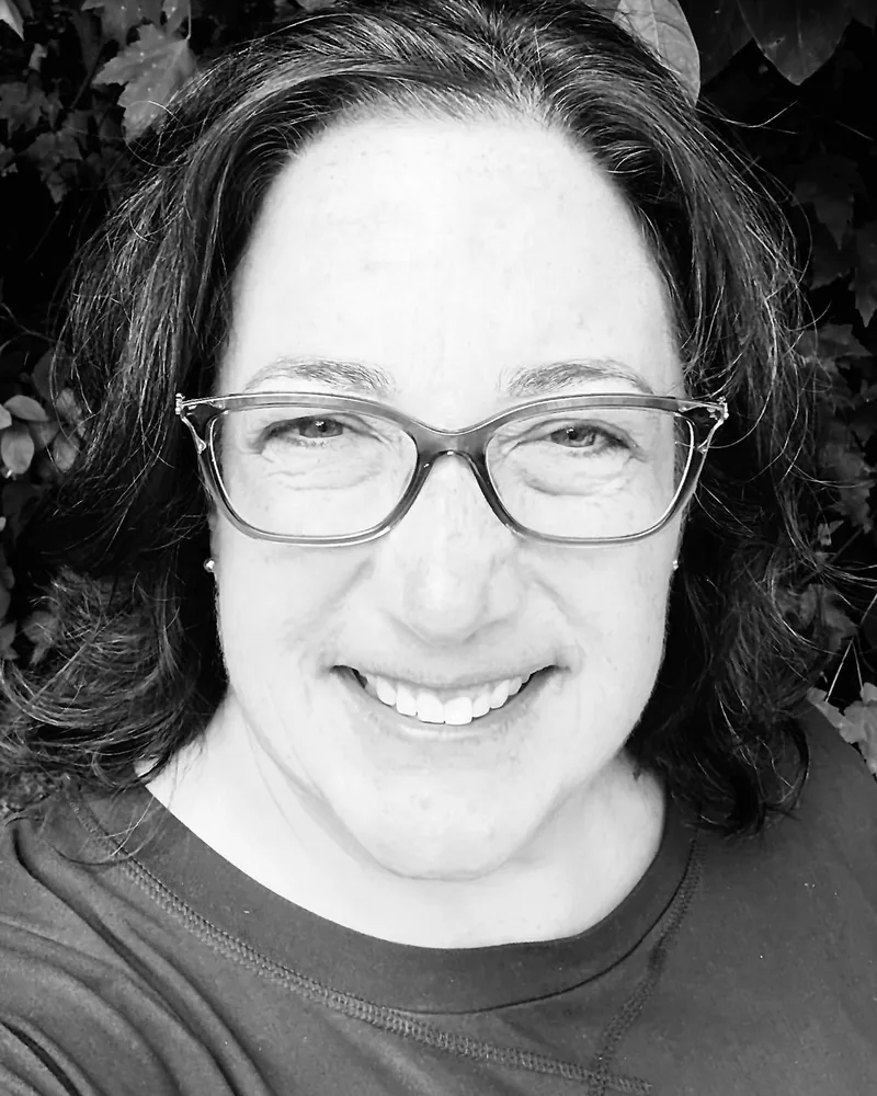 Carolyn Russo, art educator at The Boston Artistry, smiling in glasses in a black and white portrait