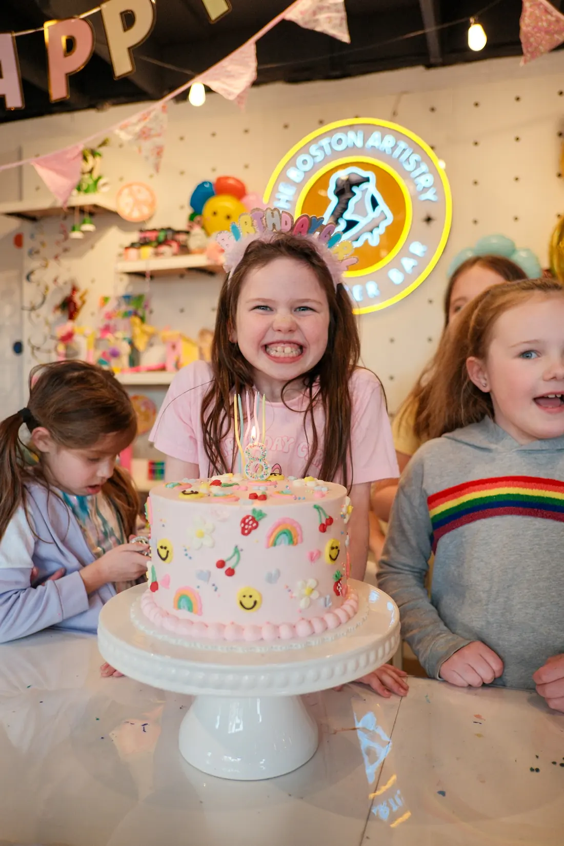 A birthday girl smiles over her cake with the candles lit