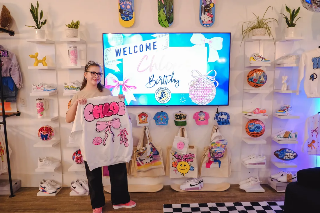 A birthday girl in a tiara wears the sweatshirt she painted