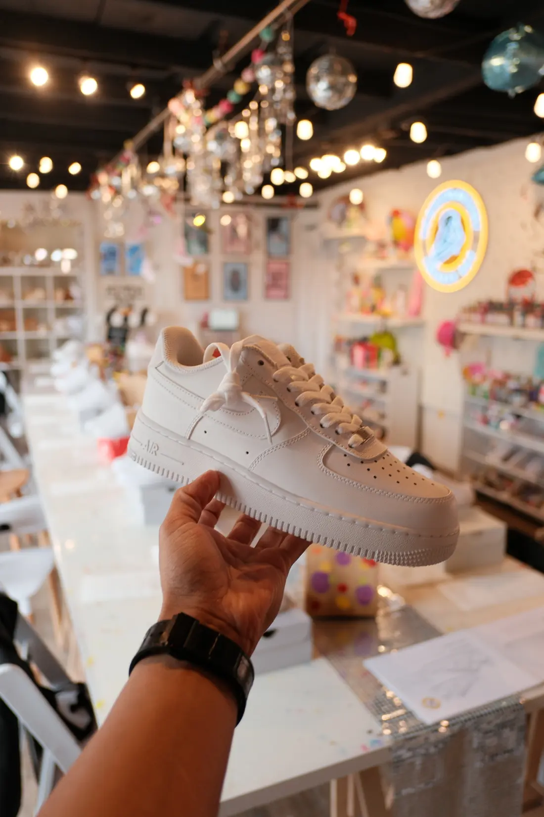 A blank all white low top sneaker held above the studio table, ready to paint