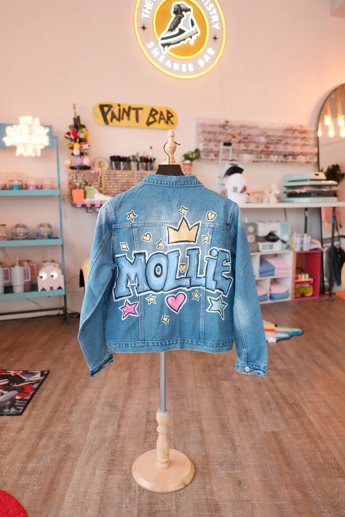 A denim jacket painted with bubble letters and a smiley on the back