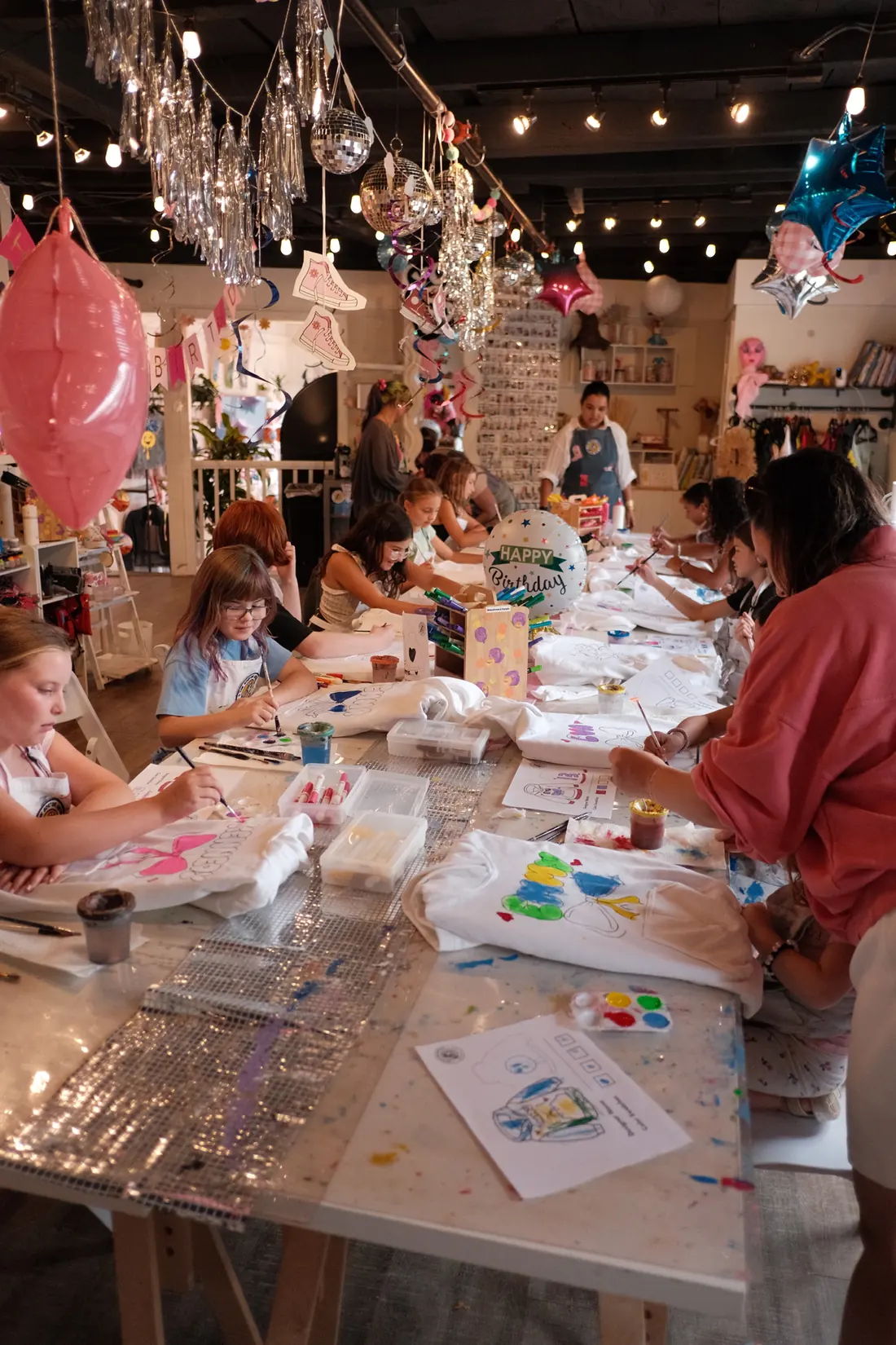 Girls paint white T-shirts around the party table at The Boston Artistry