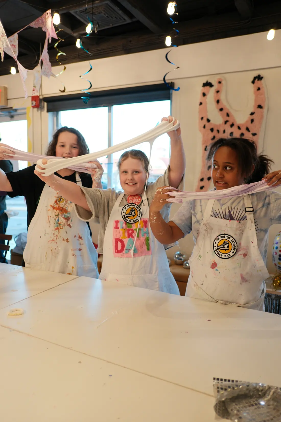 Girls stretch slime high above the party table