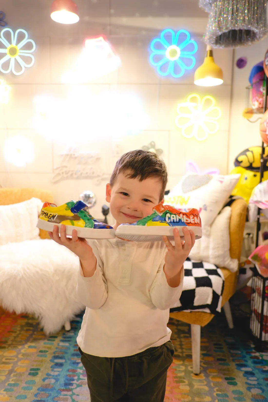 A small boy holds up his hand lettered custom sneakers
